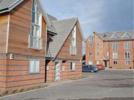 Red brick building with angular roof with another similar structure in the background