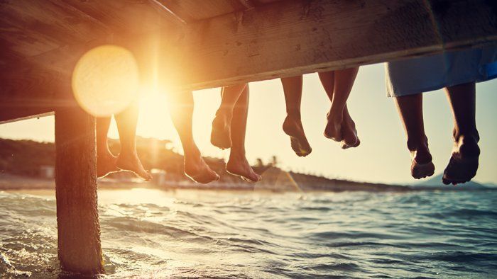 group of friends sitting on a pier with feet dangling