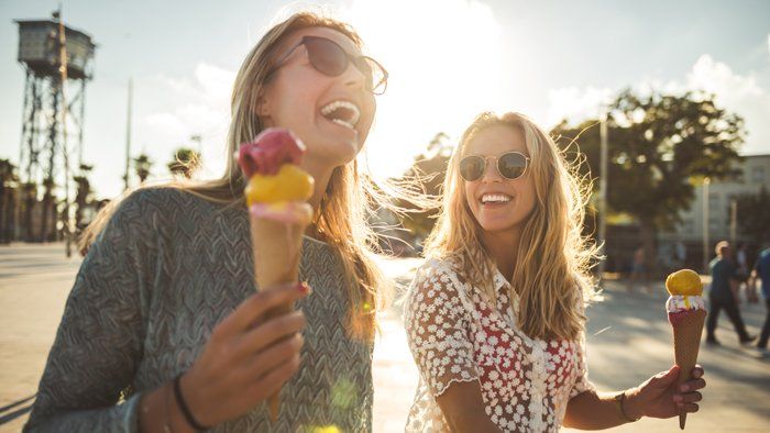 2 girls laughing with ice cream cones in their hands