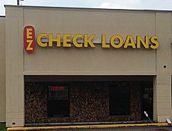 EZ Check Loans store sign. Yellow lettering on tan building. Red 