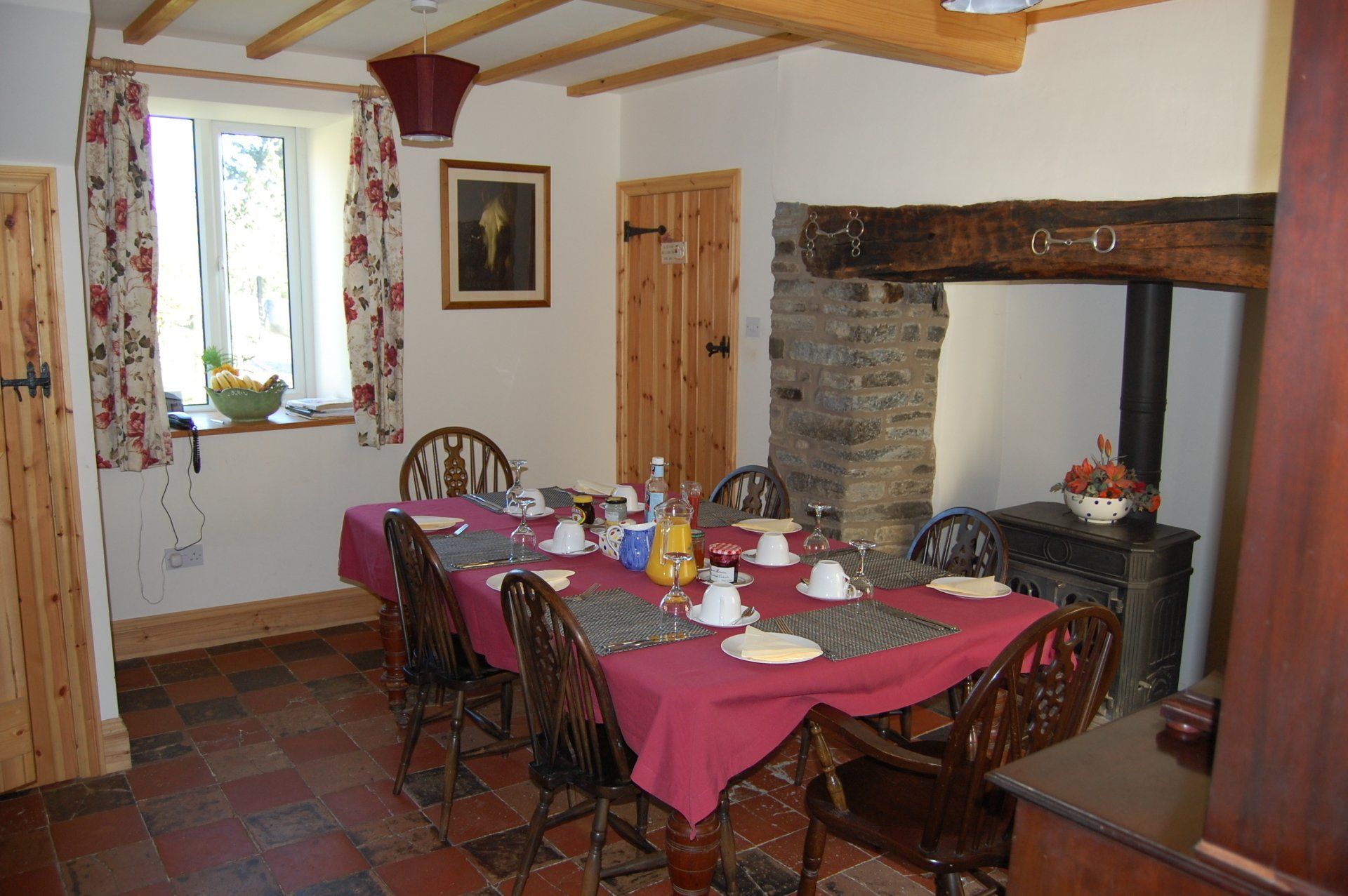Dining room with a table set for a meal, a fireplace, and a window with curtains.
