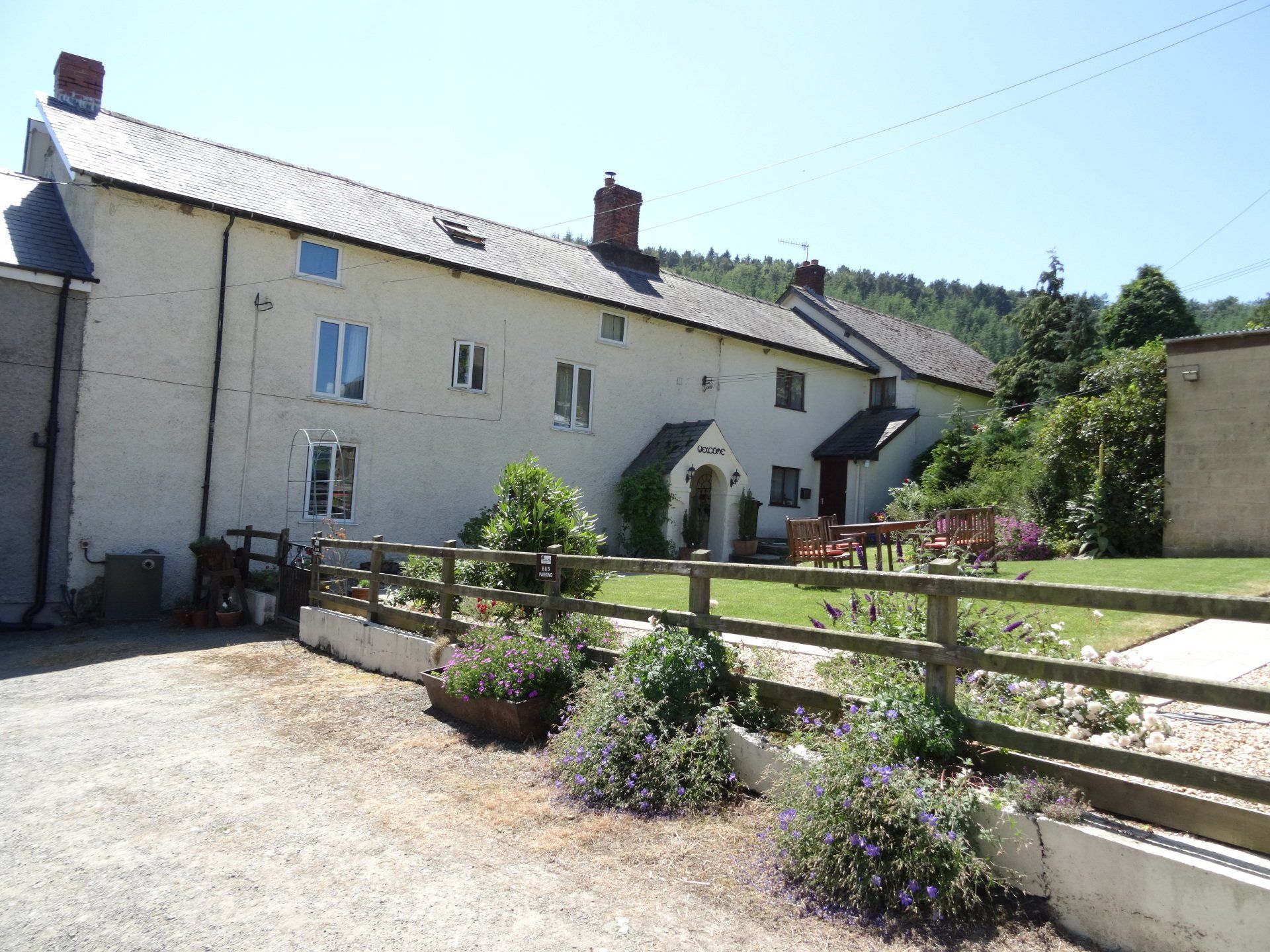 Whitewashed cottages with a wooden fence and garden.