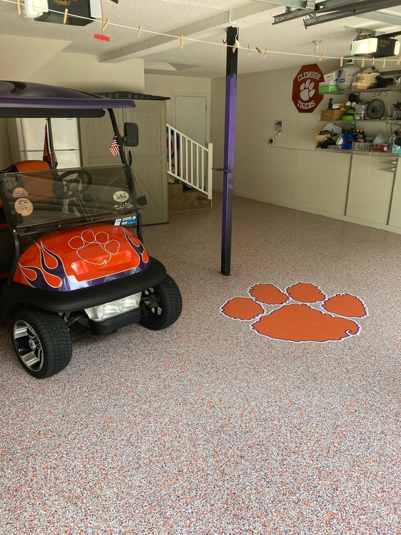 Garage with a Clemson University theme, featuring a golf cart with orange detailing, a paw print on the floor.