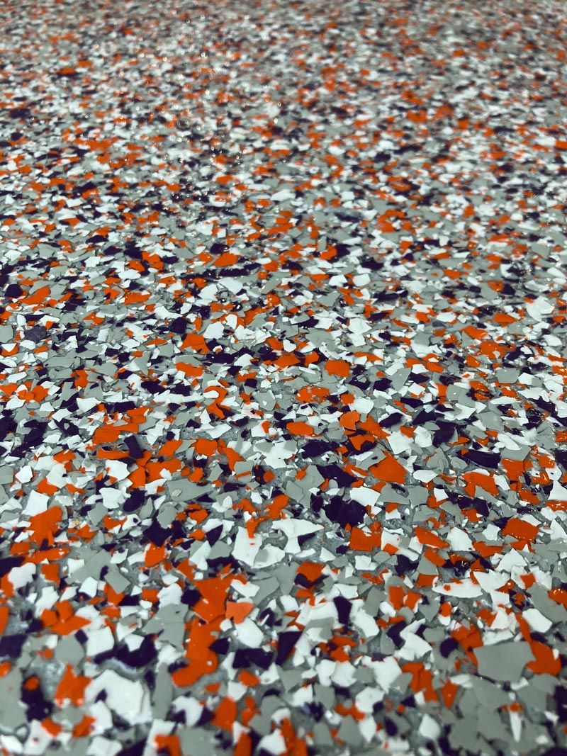 Close-up of a speckled floor with chips of orange, gray, white, and black.