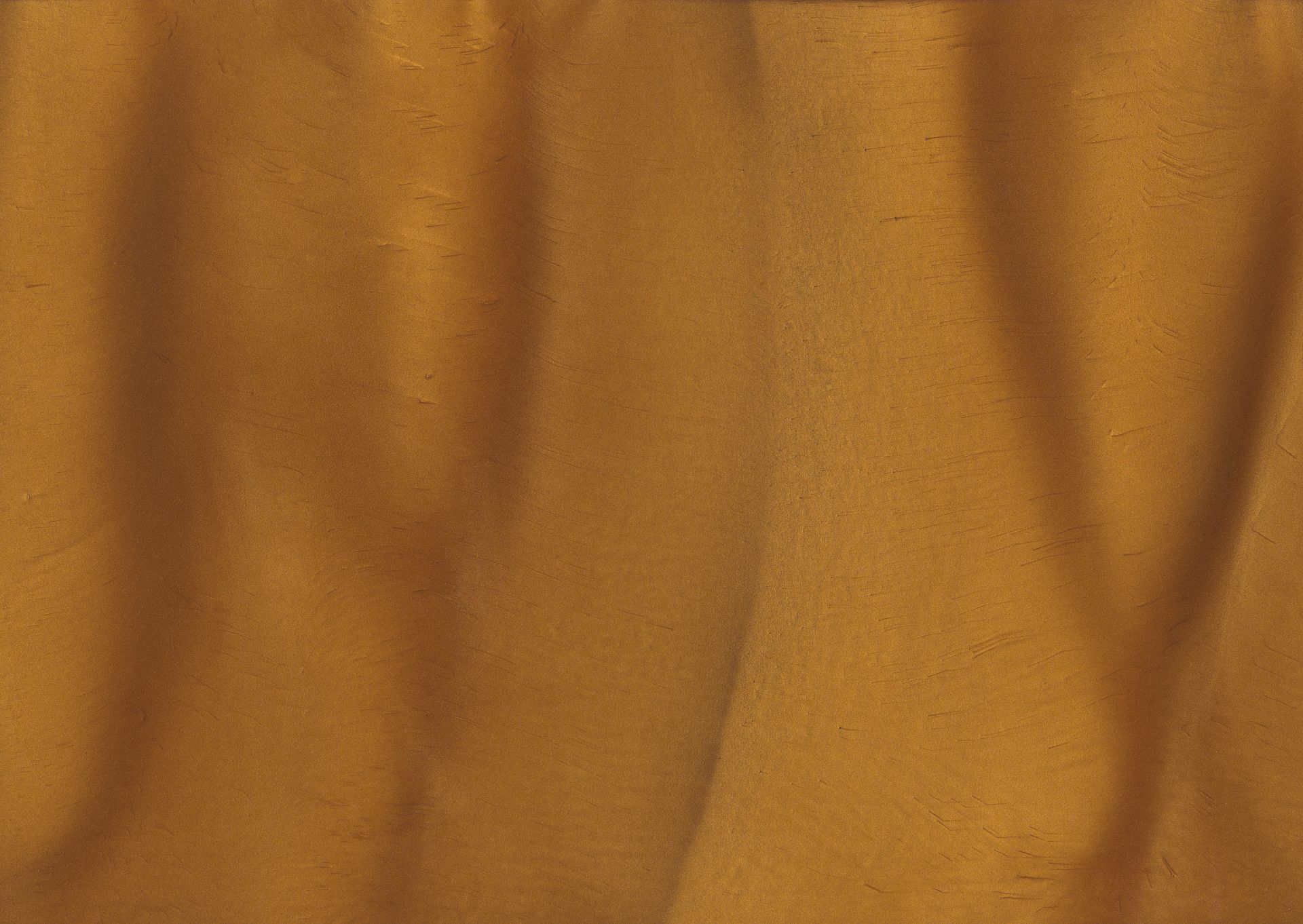 Close-up of a textured, amber-colored surface with vertical folds, possibly fabric or wood grain.