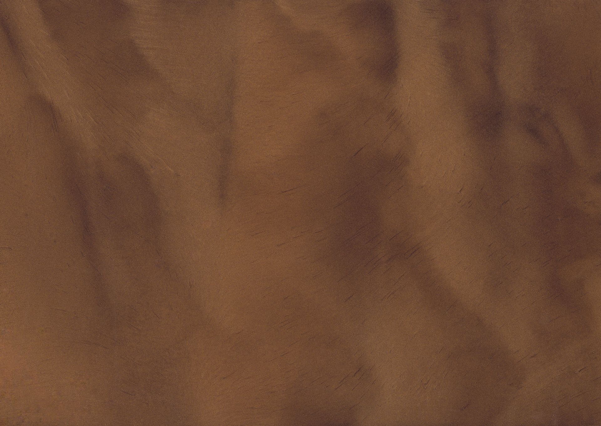 Brown sand with wave-like patterns and varying shades of light and dark, suggesting movement.
