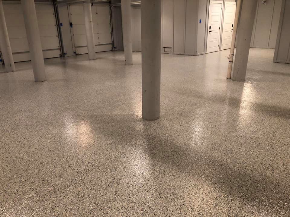 A polished concrete floor speckled with gray and white aggregate in a room with support pillars.