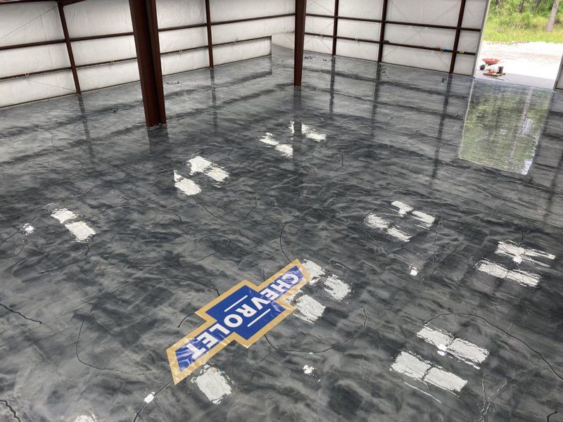 Shiny, metallic gray epoxy floor with a blue and yellow Chevrolet logo. A warehouse interior with reflective surfaces.