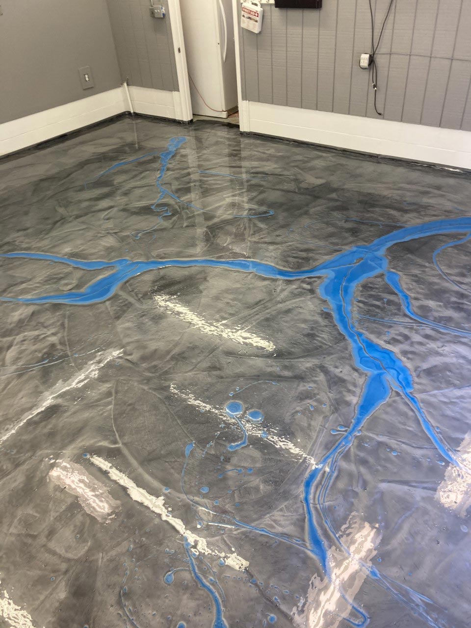 Gray and silver epoxy floor with streaks of white and blue, in an empty room.