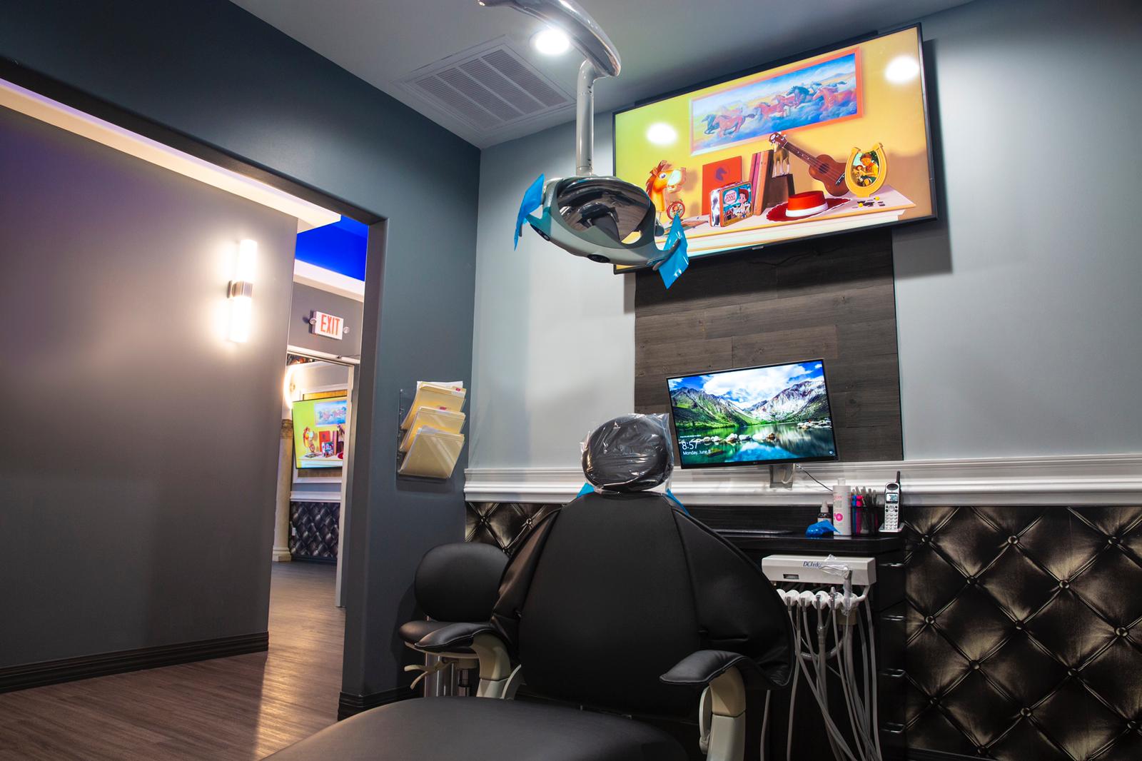 Modern office lounge with black chairs, wall-mounted TV, and colorful ceiling decor