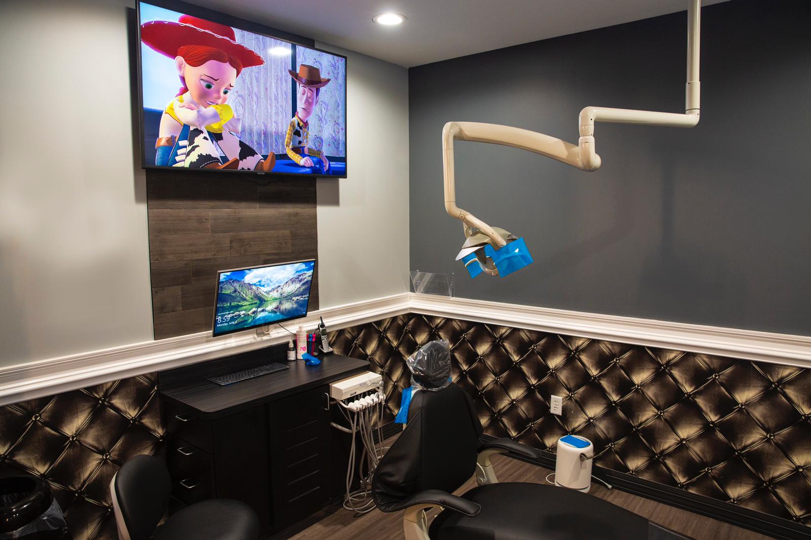 Home office with a wall-mounted TV and monitor, black tufted seating, and a white boom-arm microphone setup.