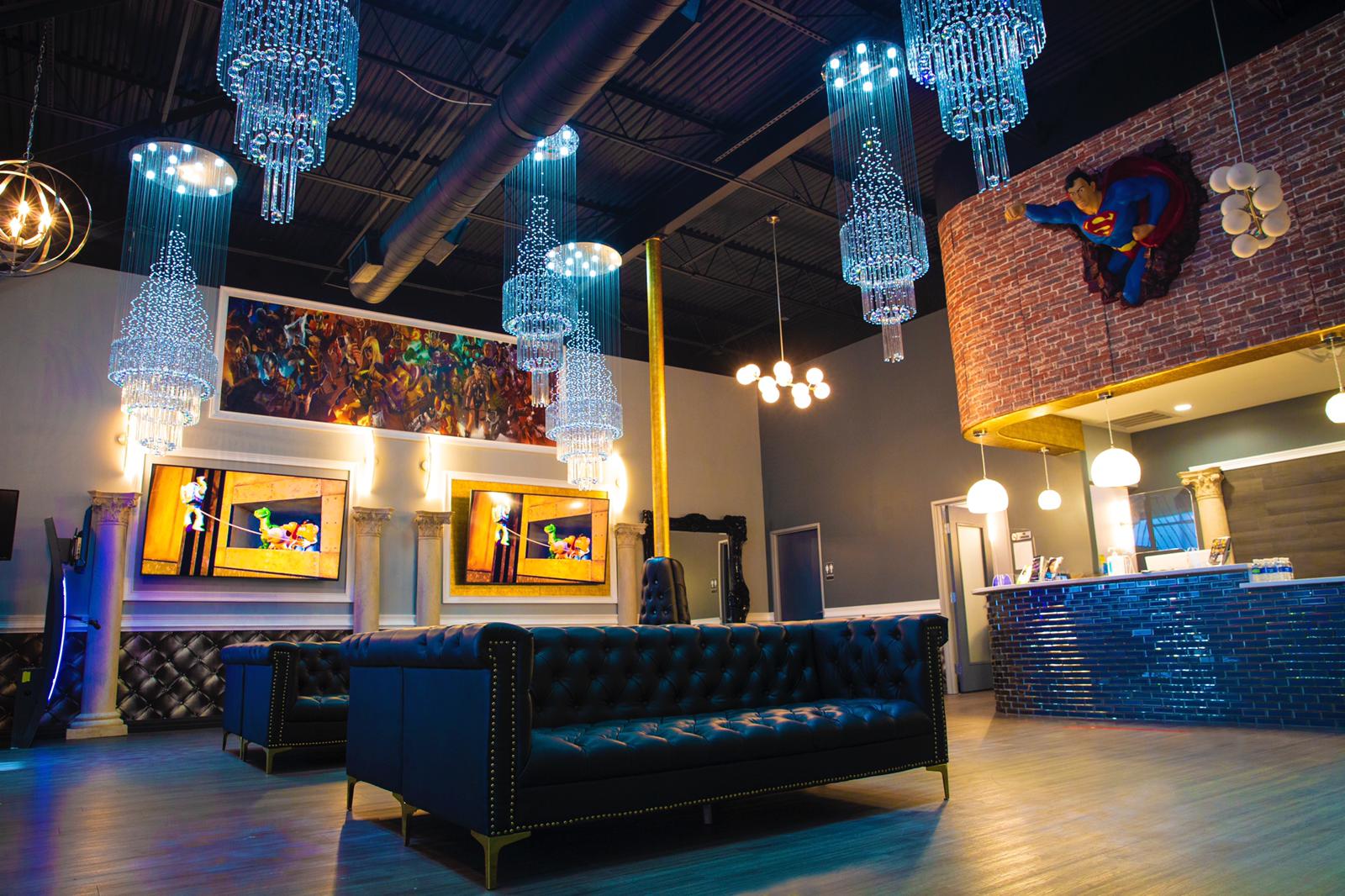 Stylish lounge with blue chandeliers, tufted seating, and illuminated wall art in a modern interior
