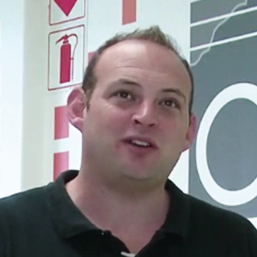A man in a black shirt is standing in front of a fire extinguisher sign