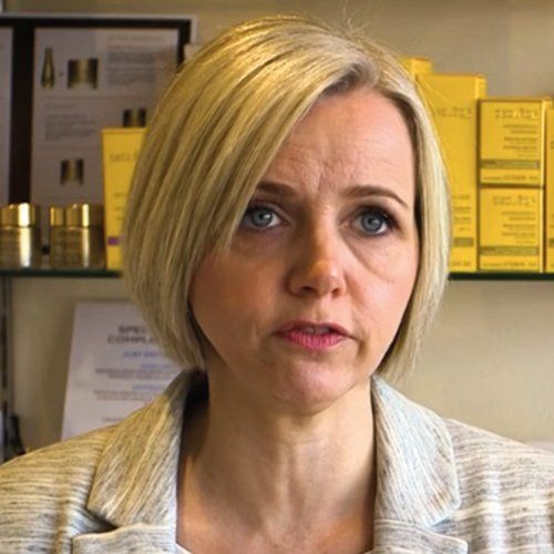 A woman is standing in front of a shelf with yellow boxes on it.
