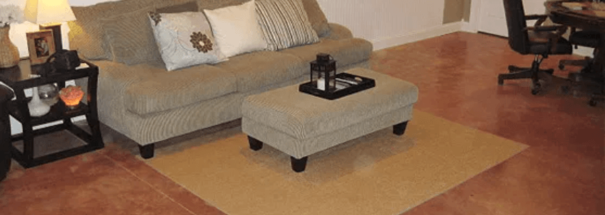 Living room with beige sofa, ottoman, lamp tables, and tan rug on hardwood floor