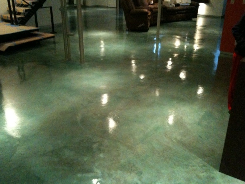 Shiny green-tinted floor in an indoor space with reflections and tables along the sides
