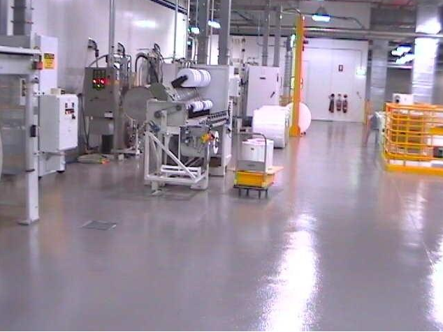 Empty industrial workshop with machinery, control panels, and polished concrete floor