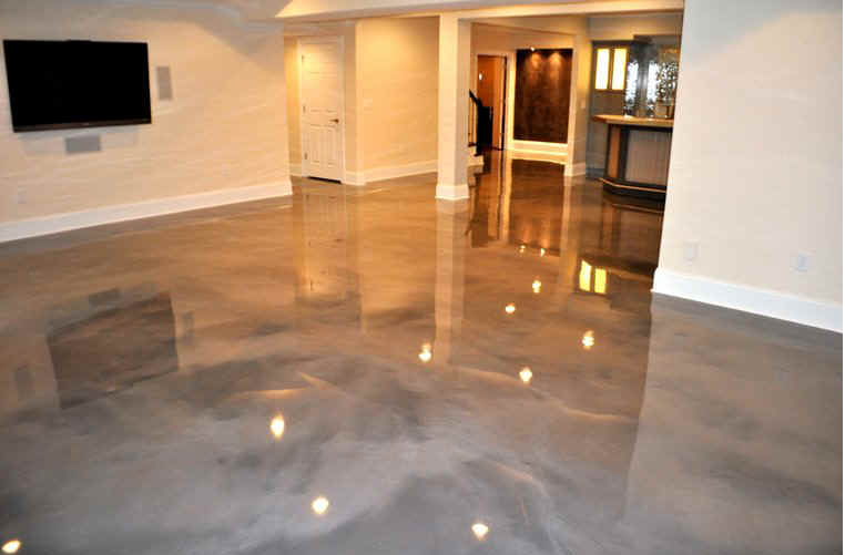 Modern living room with glossy gray epoxy floor, wall-mounted TV, and open kitchen area