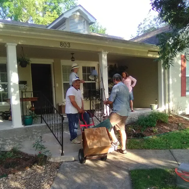 A group of people standing outside of a house with the number 803 on it