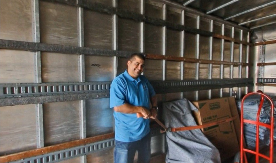A man in a blue shirt is standing in the back of a moving truck