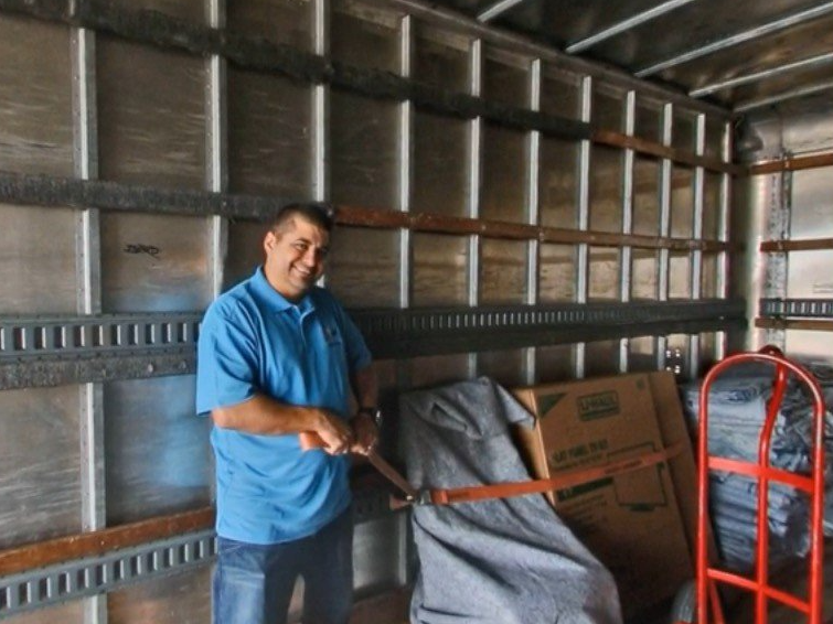 A man in a blue shirt is standing in a moving truck