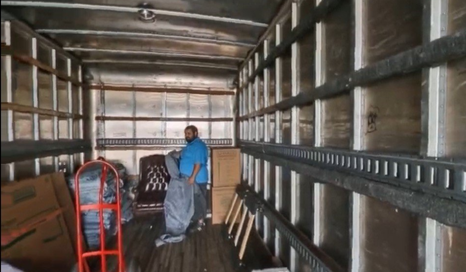 A man is standing in the back of a moving truck.
