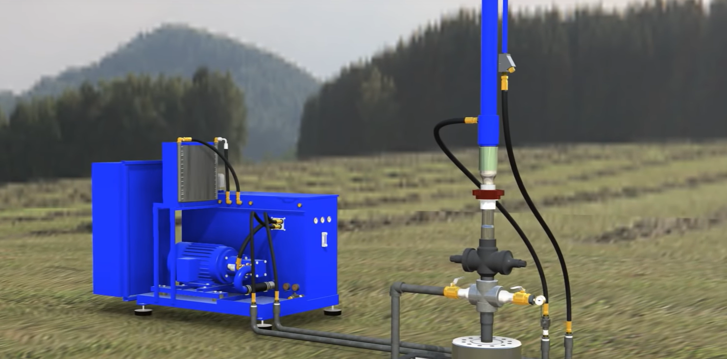 Blue industrial machine in a field, connected to piping and hoses with hills in the background