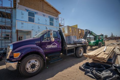 A purple truck is parked in front of a building under construction | Roofing Contractors Denver CO