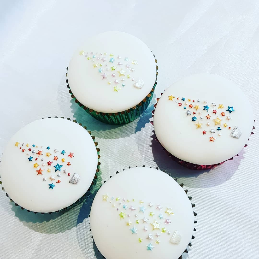 Four cupcakes with white frosting and sprinkles on them