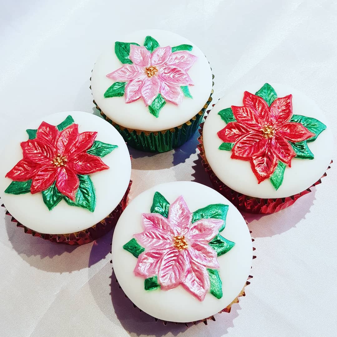 Four cupcakes with red and pink flowers on them
