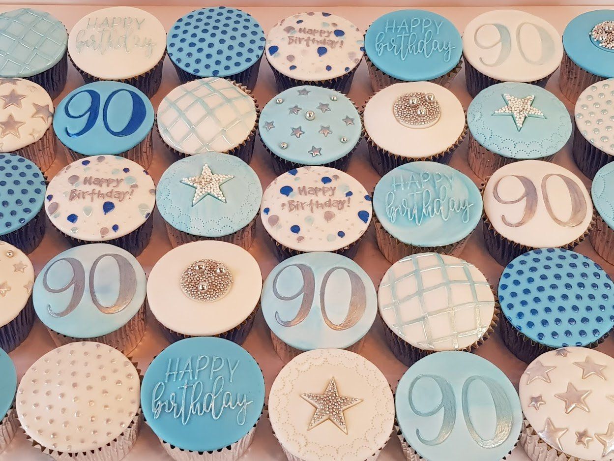 A bunch of blue and white cupcakes with the number 90 on them