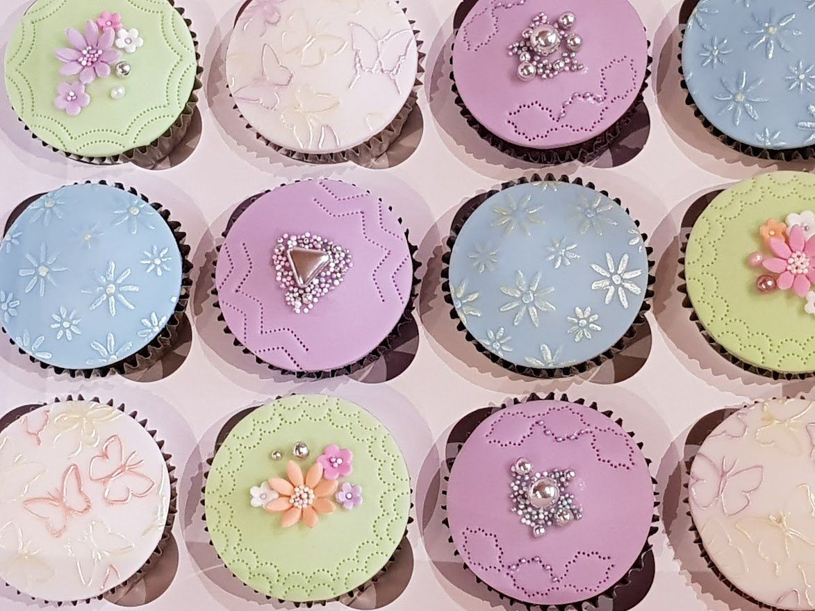 A box of cupcakes with flowers and rhinestones on them