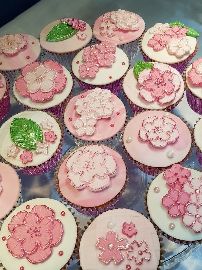 A bunch of pink and white cupcakes with flowers on them