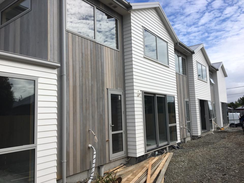 A row of white houses with a lot of windows are being built.