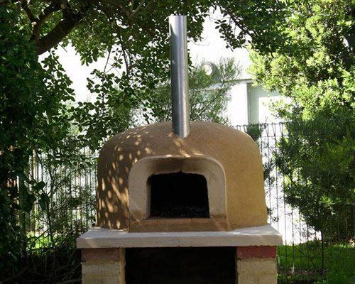 wood fire pizza oven underneath trees