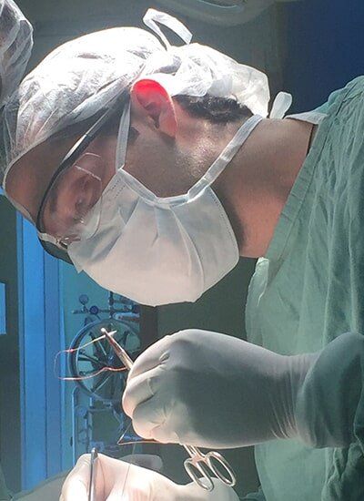 Cirujano proctólogo Dr. Marco Boca concentrado durante una intervención quirúrgica en quirófano