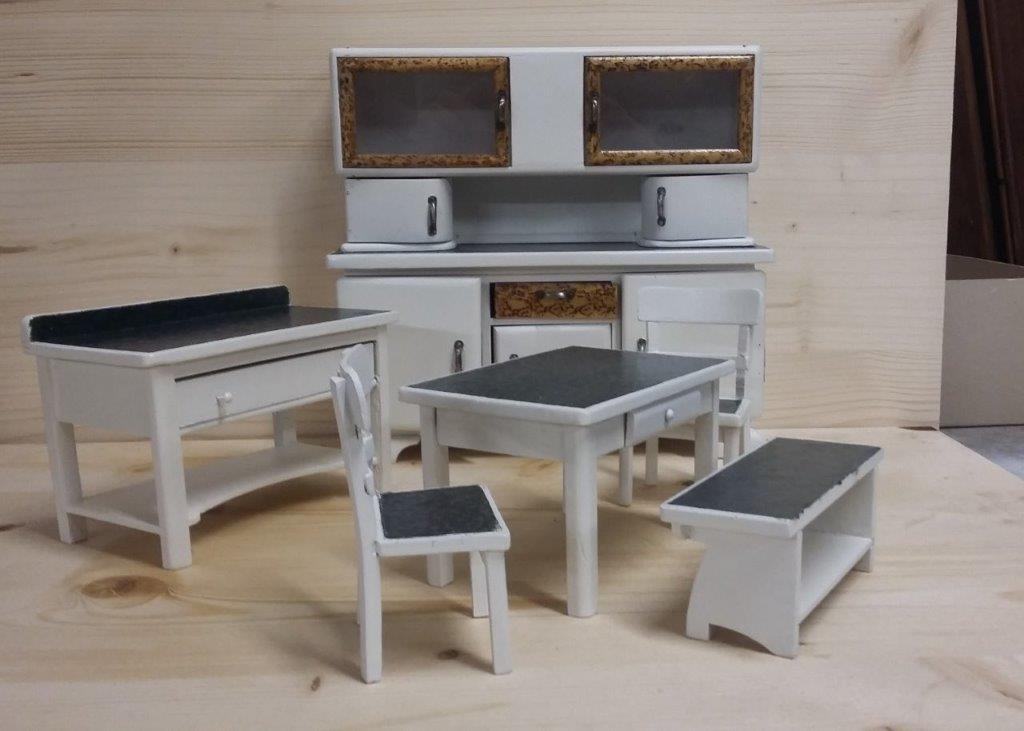 Miniatur-Puppenhausküche und Essgruppe in Weiß mit schwarzen Kissen auf Holzboden