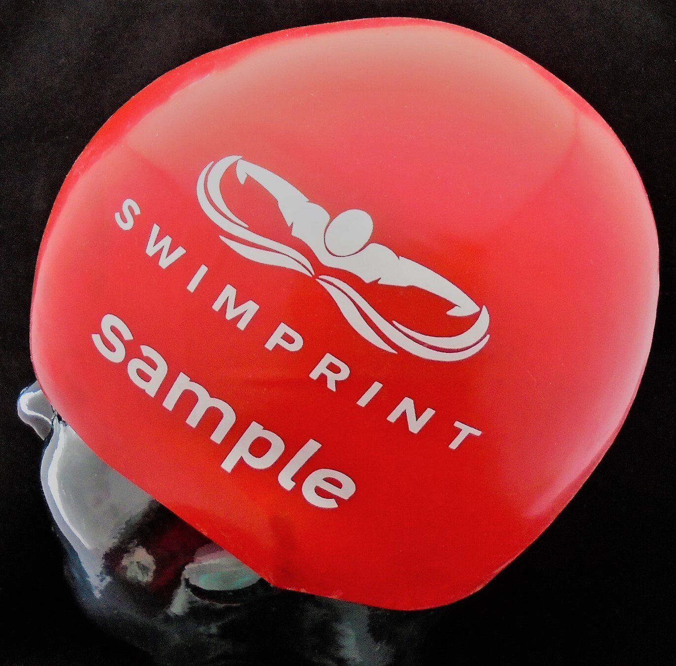 A red swimprint sample swimming cap on a black background