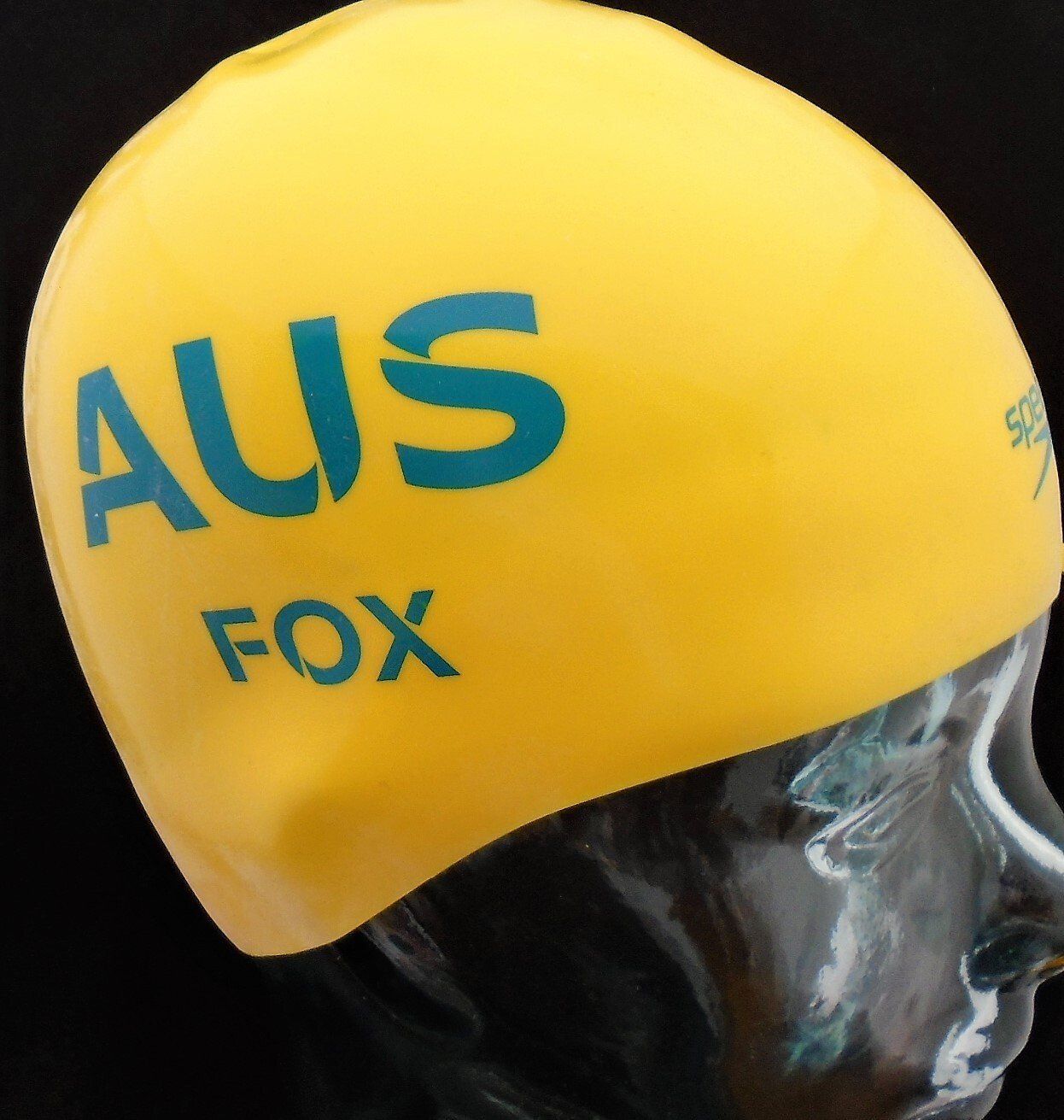 A yellow swim cap that says aus fox on it