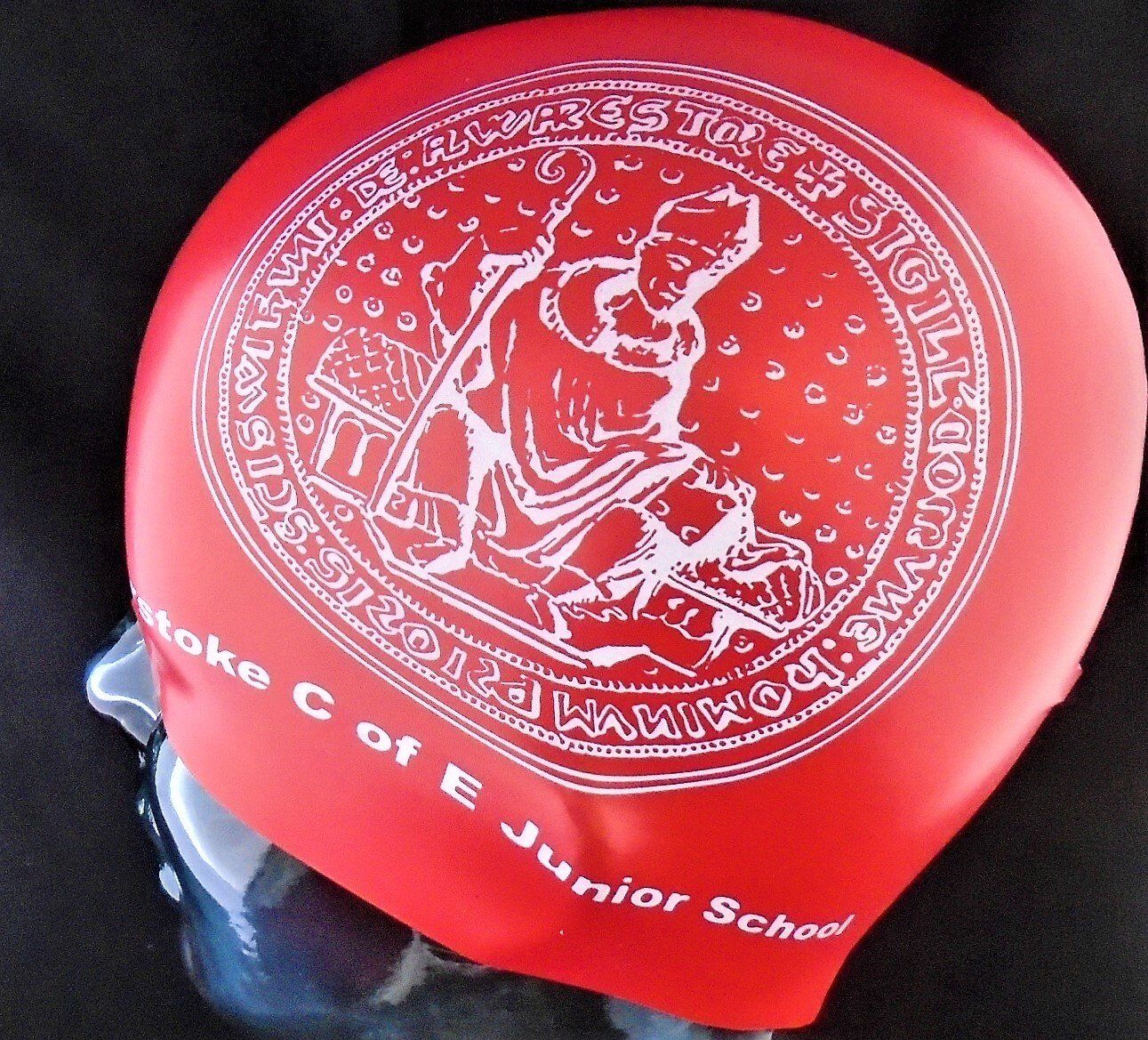 A red swim cap that says moke c of e junior school