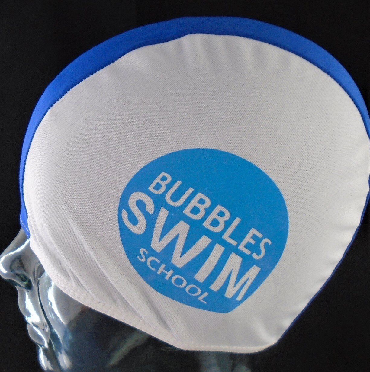 A white and blue swim cap that says bubbles swim school