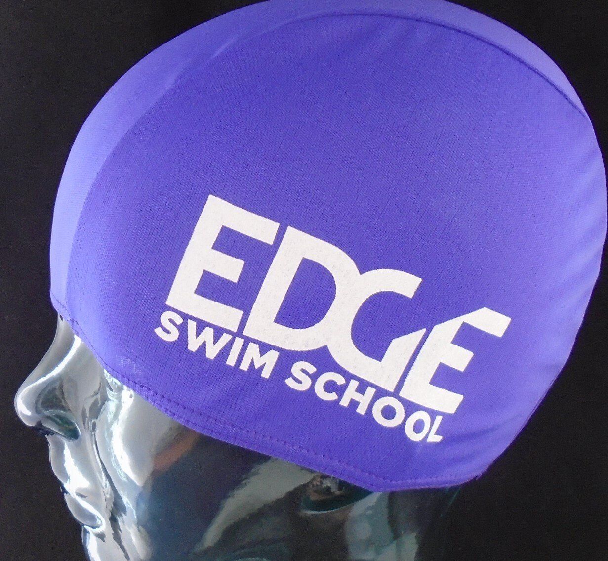 A purple swim cap that says edge swim school