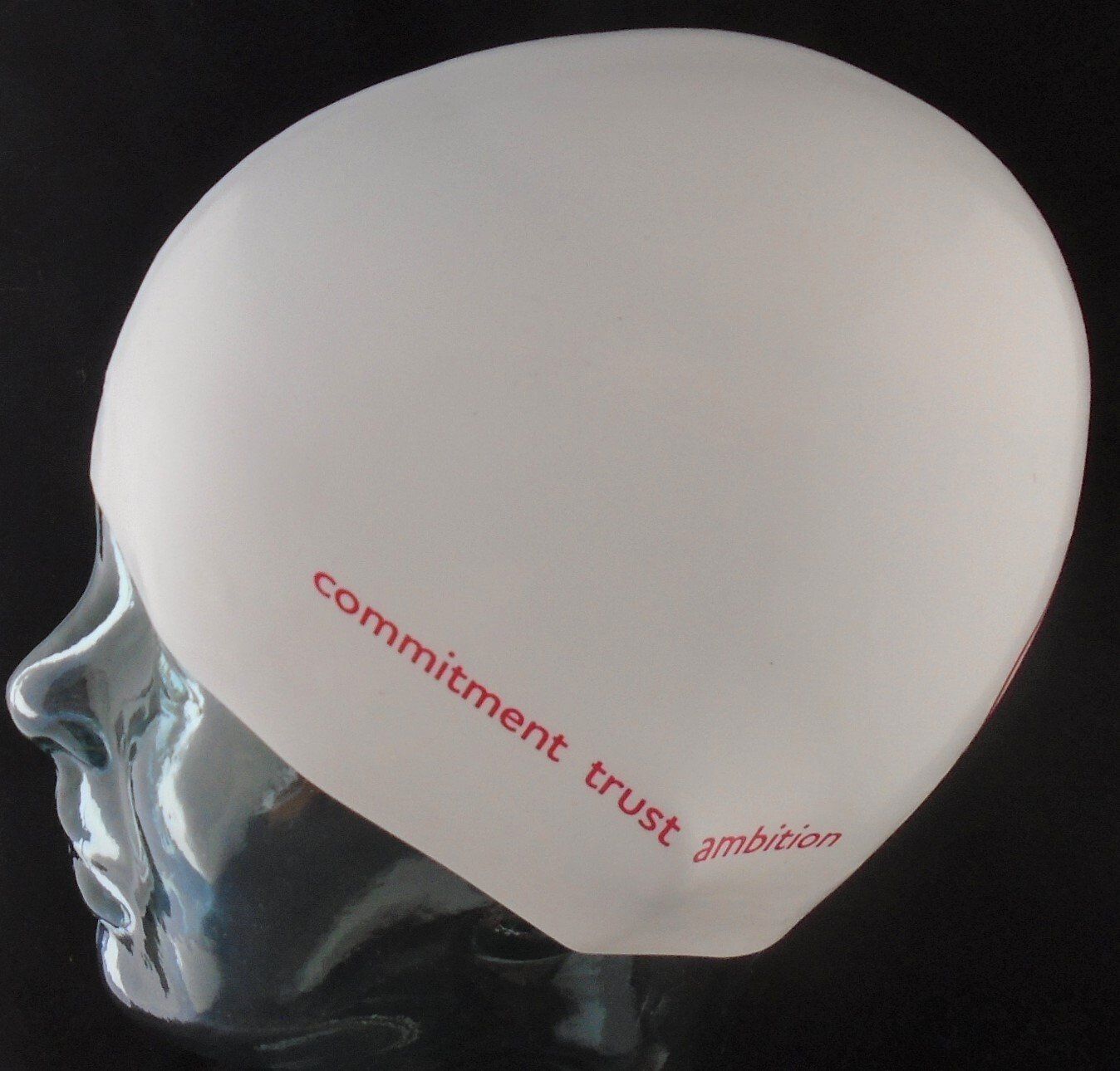 A white swim cap that says commitment trust ambition