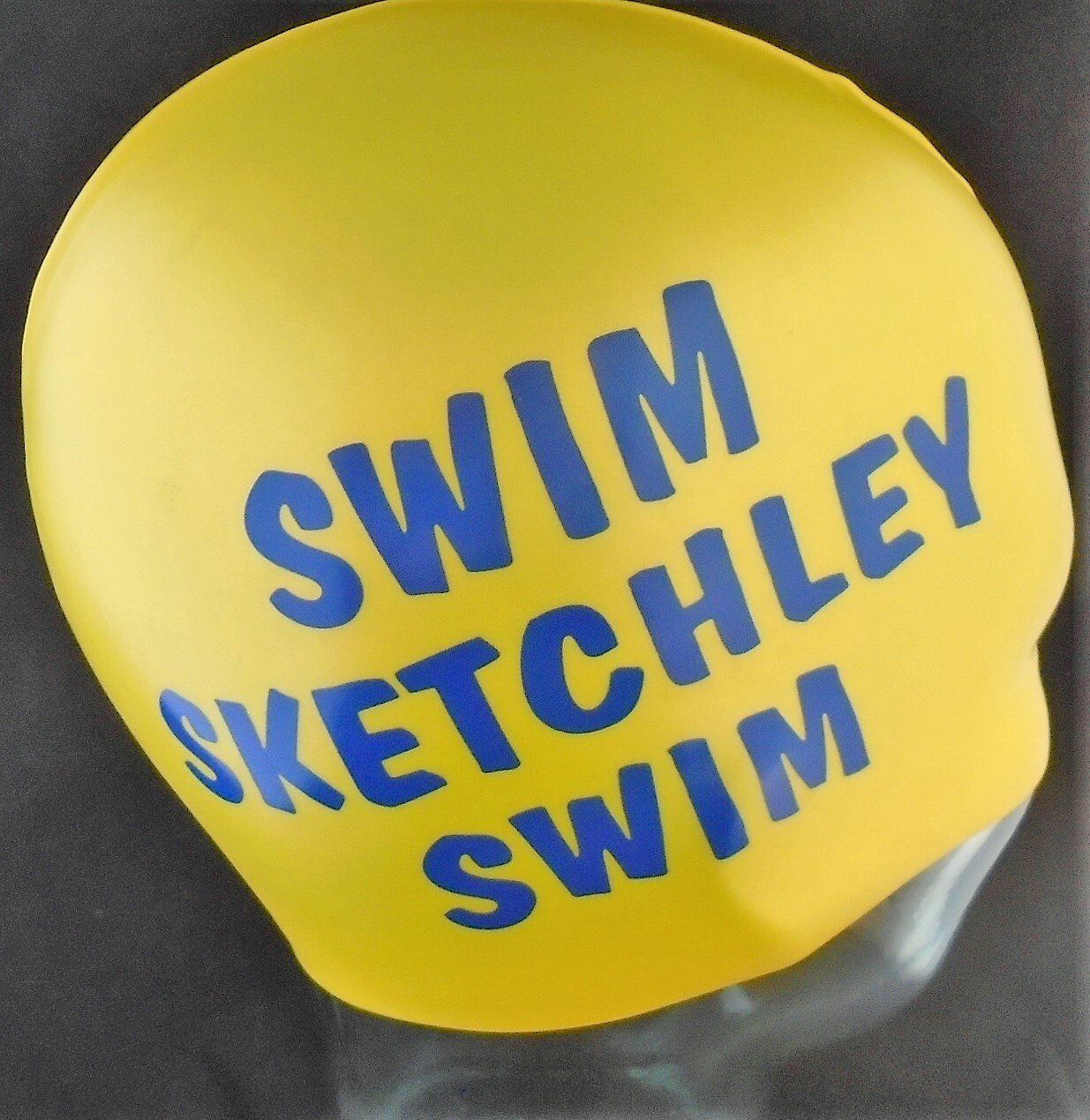 A yellow swim cap that says swim sketchley swim