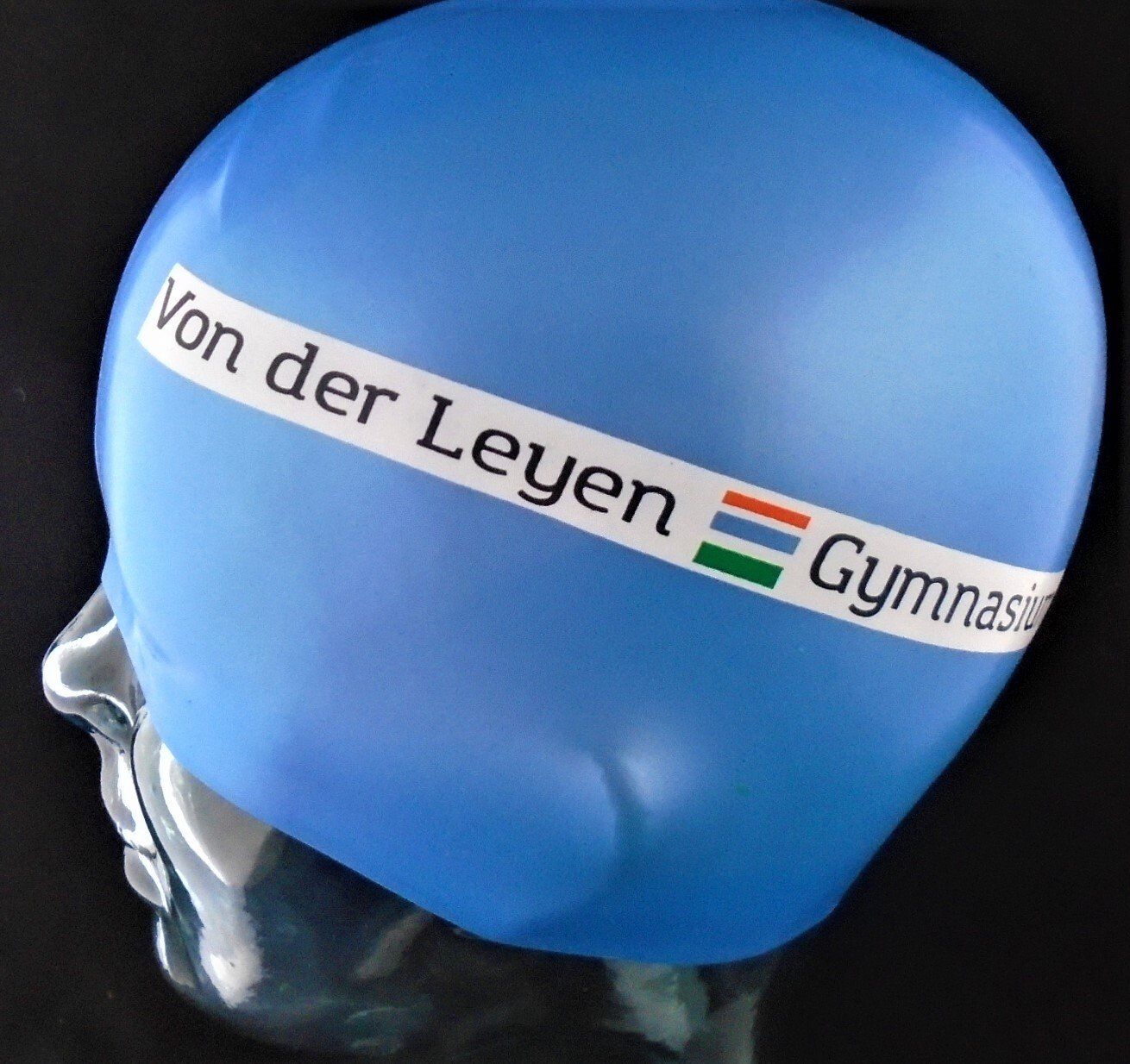 A blue swim cap that says von der leyen on it