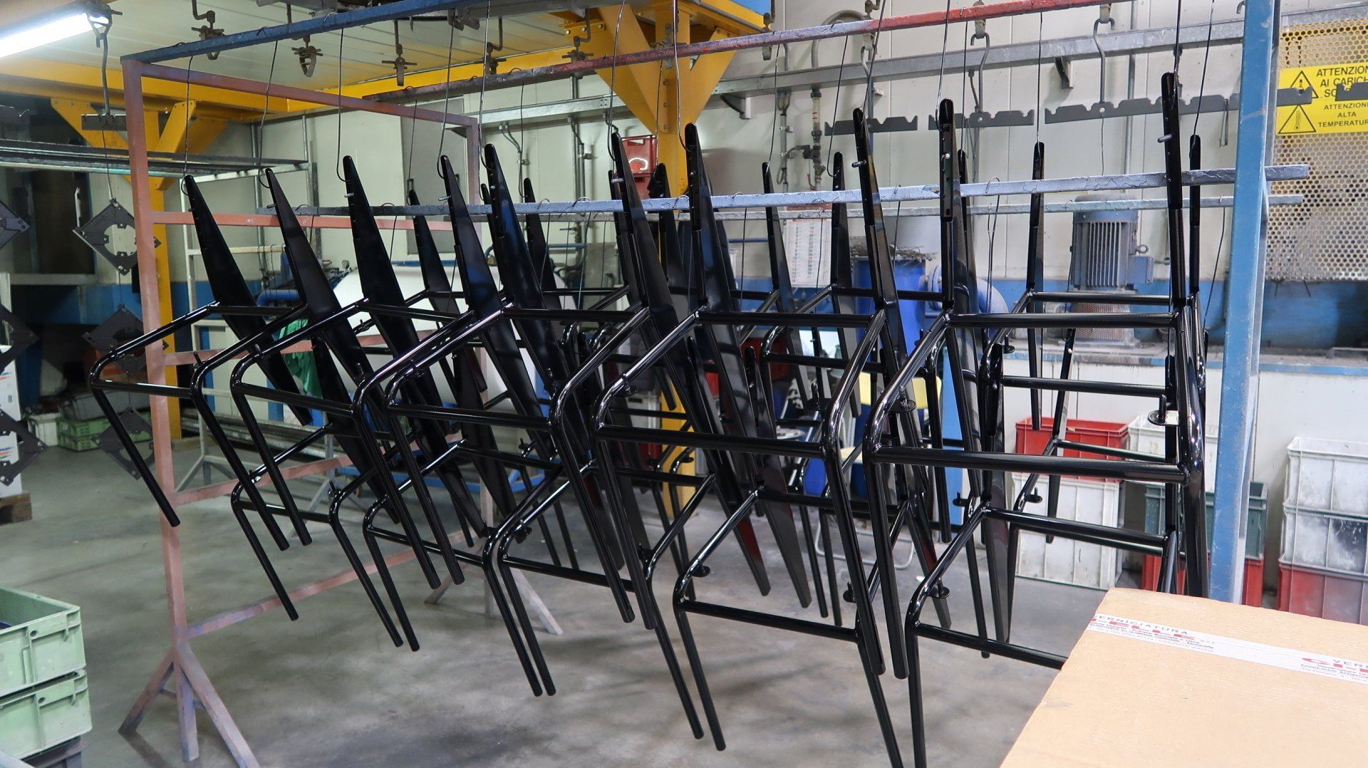 File di scaffalature metalliche nere appese in un'officina o fabbrica industriale.