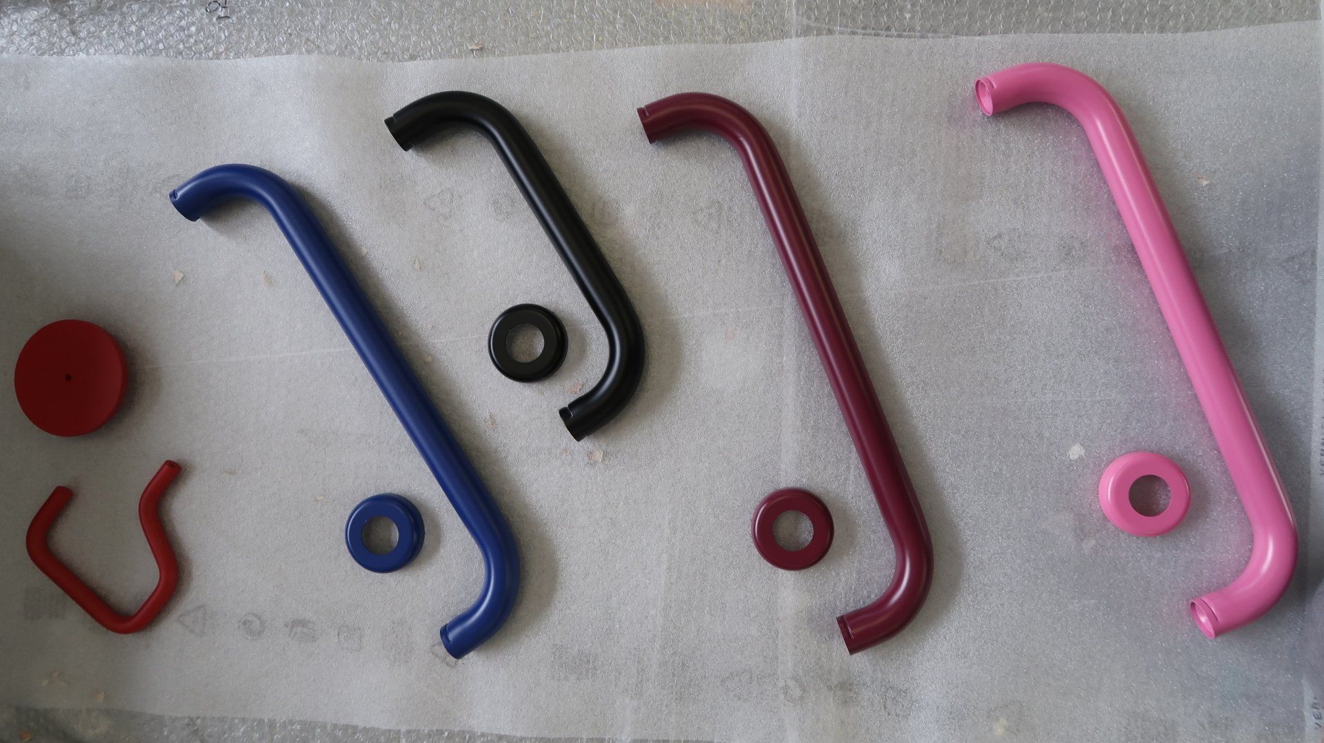 Ganci e anelli assortiti in plastica e gomma colorata, disposti su una superficie chiara.