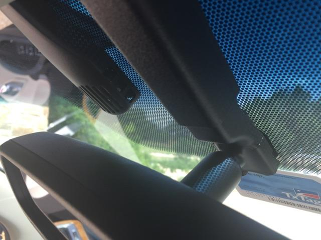 A dashcam and a rearview mirror mounted to a vehicle windshield with a blue dot-matrix pattern.