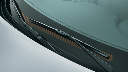 A close-up view of a car's black windshield wiper resting against the glass, with a decorative copper-colored trim.