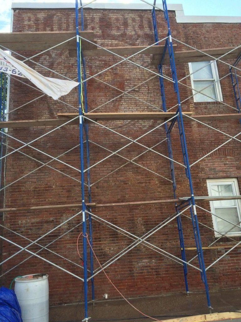 Brick building with scaffolding. Faded sign 